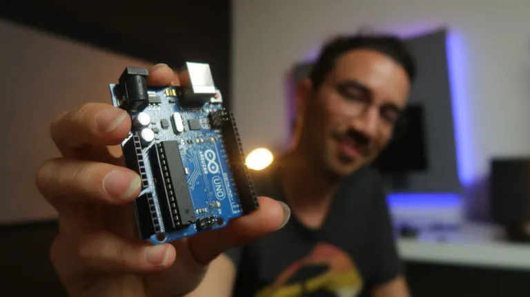 Gustavo holding an Arduino Uno board